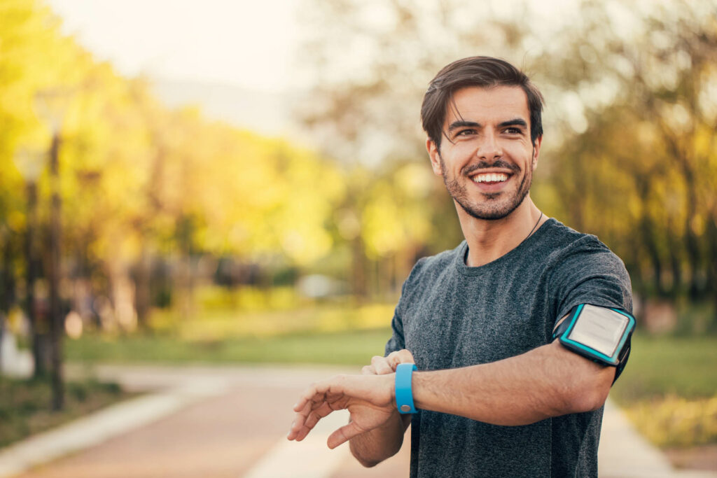 Sportsman looking at his smart watch in the park.